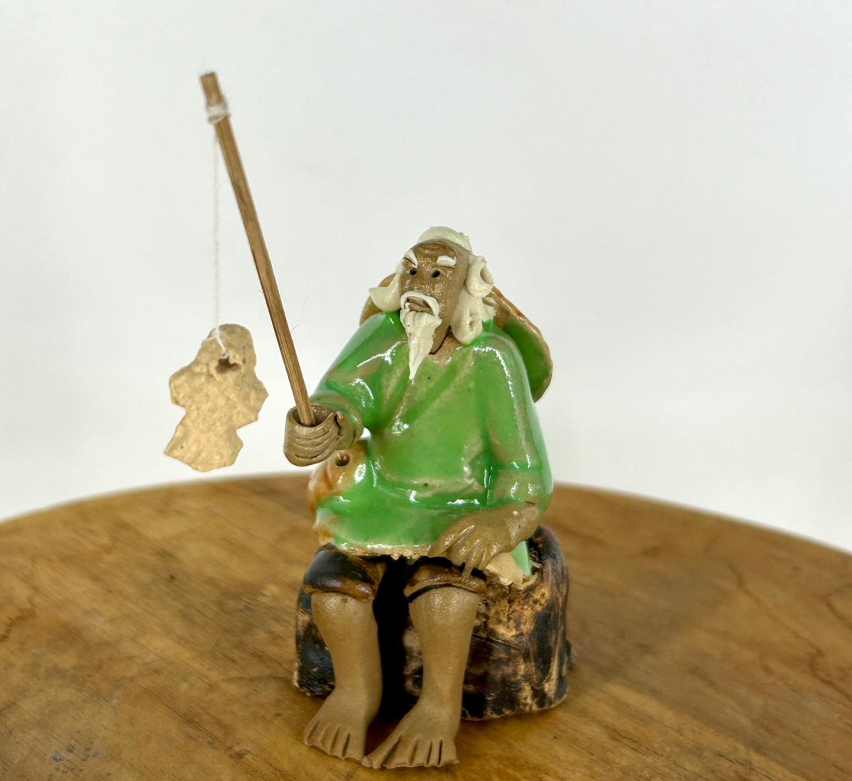 e3601 Miniature Ceramic Glazed Fisherman Figurine with Sitting On A Log, Light Green - 2.5 in.