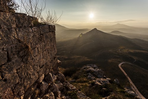 DPI12286930 Ruins of A Stone Wall with A Sunburst & Mountains - Corinth Greece Poster Print by Reynold Mainse, 19 x 12