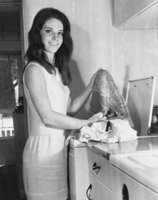 Portrait of a Young Woman Taking Clothes Out of a Washing Machine Poster Print - 18 x 24 in.