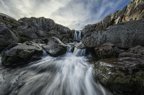 DPI12296399 Stream Flows Over A Waterfall & Through The Rocks Along The Eastern Coast of Iceland - Iceland Poster Print by Robert Postma, 19 x 12