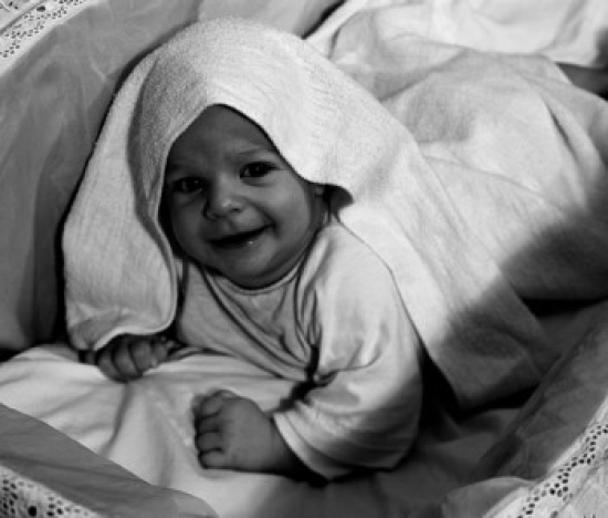 Child Smiling & Looking at Camera Covered with Blanket Poster Print - 18 x 24 in.