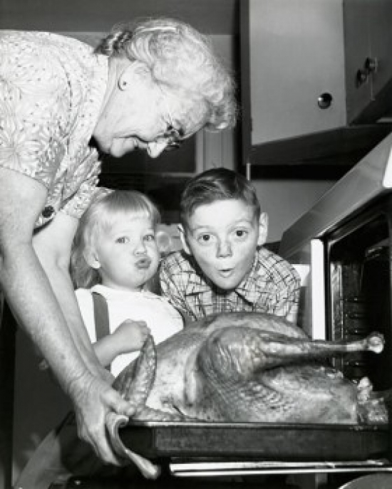 Side Profile of a Senior Woman Taking a Roasted Turkey Out of an Oven with Her Grandchildren Looking Surprised - 18 x 24 in.