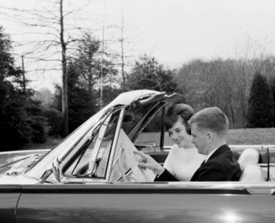 SAL2556946 Side Profile of a Young Couple Sitting in a Convertible Car Reading a Map Poster Print - 18 x 24 in.