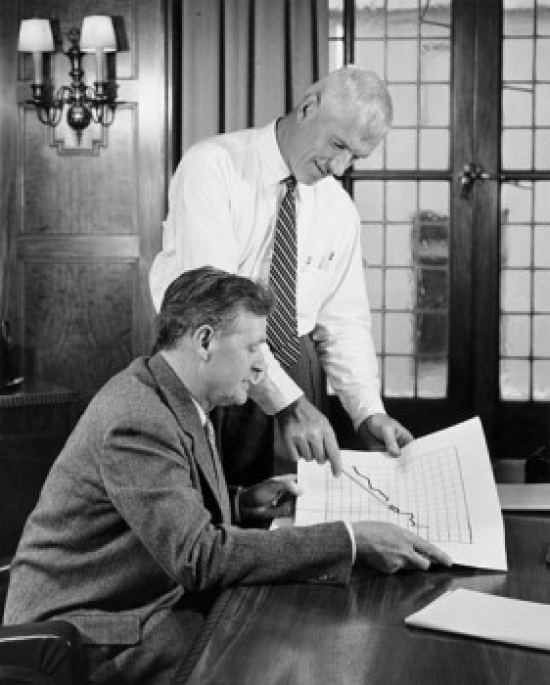 Two Businessmen Discussing Line Graph in Office Poster Print - 18 x 24 in.