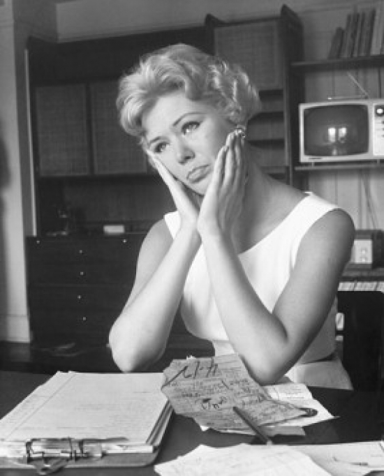 Close-Up of a Young Woman Sitting at a Table & Looking Worried Poster Print - 18 x 24 in.