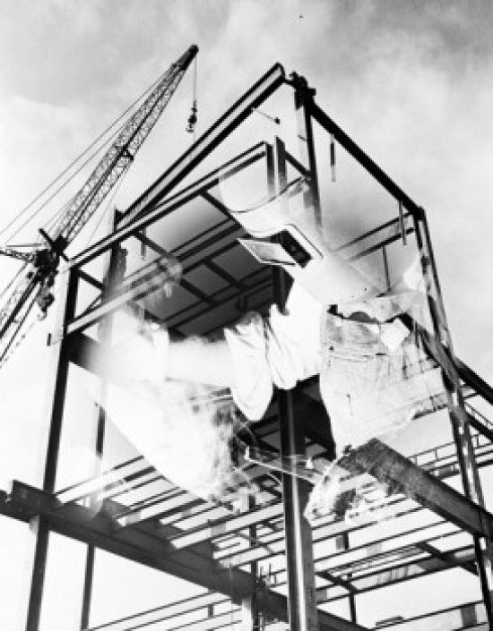 SAL255422457 Crane on Construction Site with Shadow of Welder on Foreground Poster Print - 18 x 24 in.