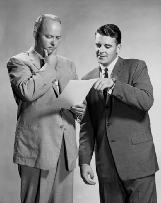 Two Businessmen Standing Discussing Document Poster Print - 18 x 24 in.