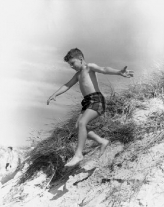 Boy Jumping From Sand Dune Poster Print - 18 x 24 in.