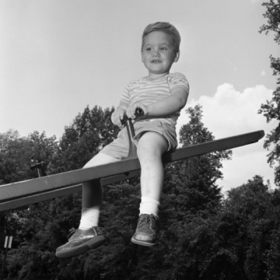 Boy Sitting on Seesaw & Smiling Poster Print - 18 x 24 in.