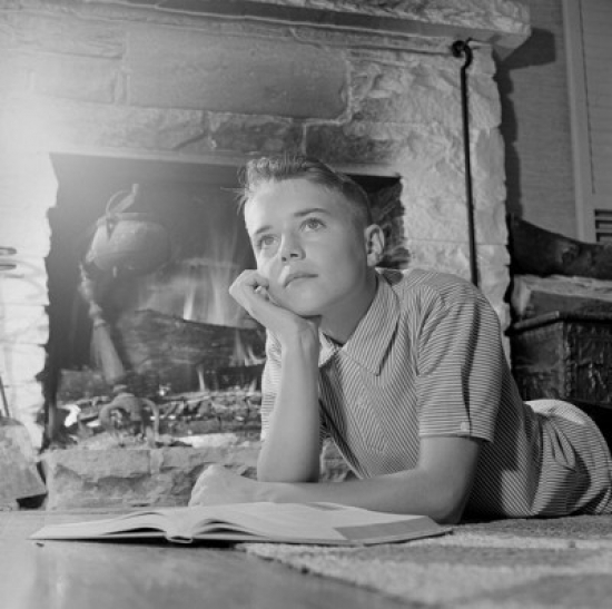 Contemplating Boy with Book by Fireplace Poster Print - 18 x 24 in.