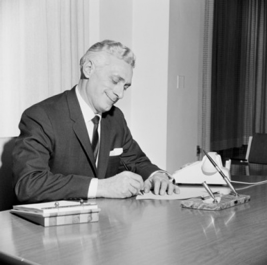 Businessman Writing Behind Desk Poster Print - 18 x 24 in.