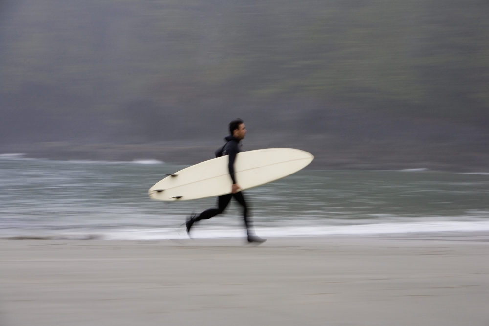 A Surfer Running with Board Along The Shoreline Poster Print by Deddeda - 17 x 11