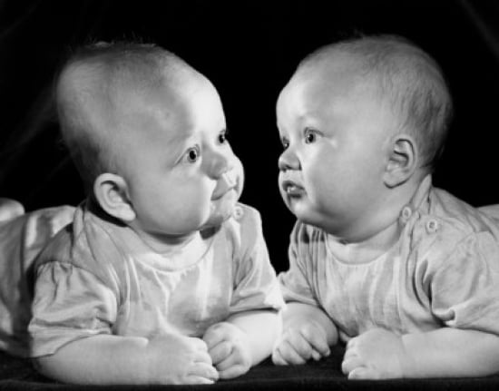 Two Babies Leaning on Elbows & Looking at Each Ether Poster Print - 18 x 24 in.