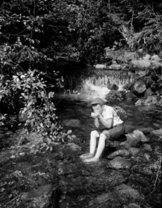Boy Sitting & Drinking Water From Mountain Stream Poster Print - 18 x 24 in.