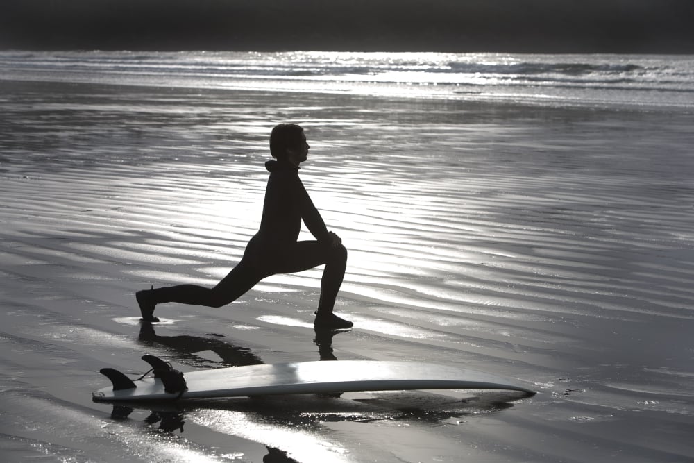Surfer Stretching On Beach Poster Print by Deddeda - 17 x 11