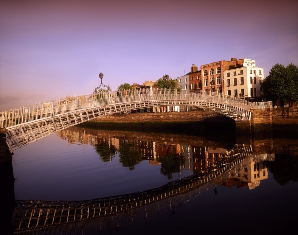 HaPenny Bridge River Liffey Dublin Ireland - Bridge Reflected in River Against Cityscape Poster Print by The Irish Image Collection - 17 x 13