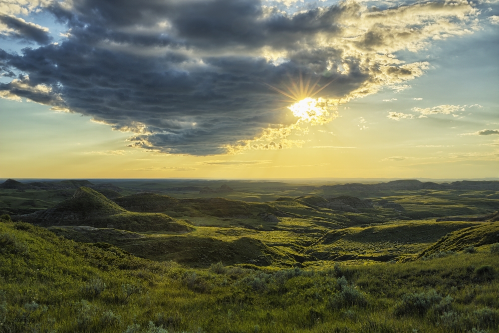 DPI12252437 The Sun Shines Through A Cloud Over The Killdeer Badlands Grasslands National Park - Saskatchewan Canada Poster Print - 19 x 12 in.