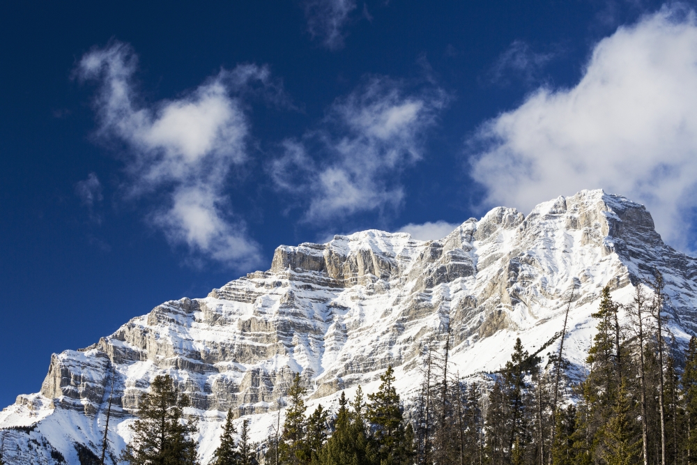 Snow Covered Mountain Peak with Evergreen Trees with Blue Sky & Clouds - Banff Alberta Canada Poster Print - 19 x 12 in.