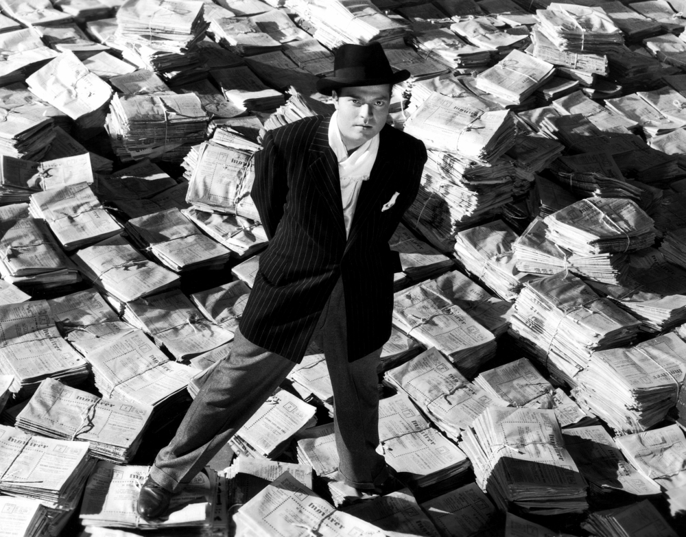 Everett Collection EVCMBDCIKAEC019HLARGE Citizen Kane Orson Welles 1941 Astride Stacks of Newspaper Photo Print, 28 x 22 - Large