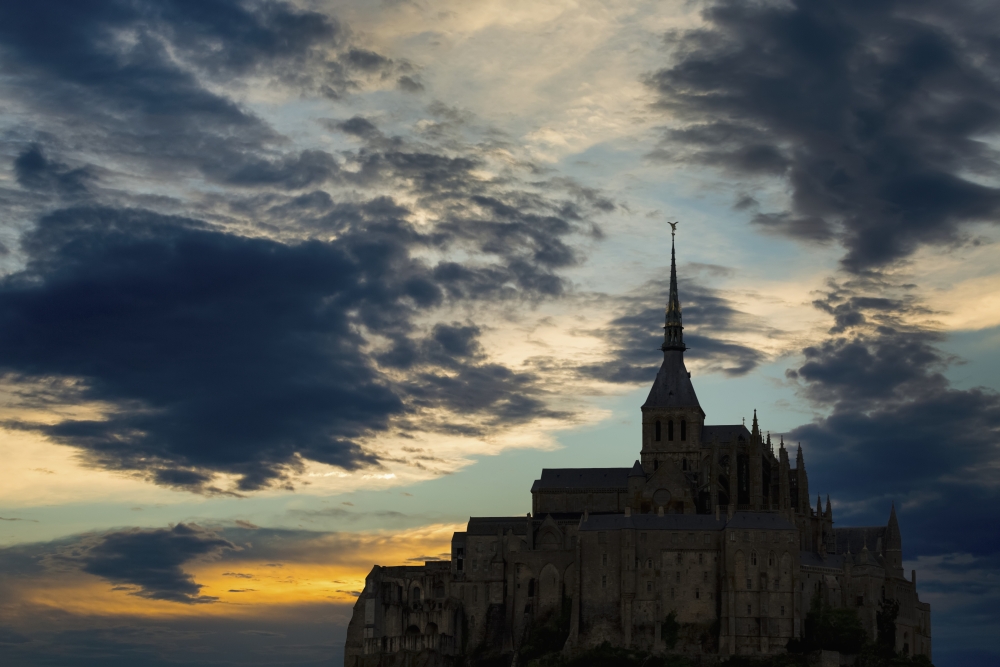 Silhouette of Large Stone Abbey Perched on Rocky Hill with Dramatic Clouds at Sunset Poster Print - 19 x 12 in.