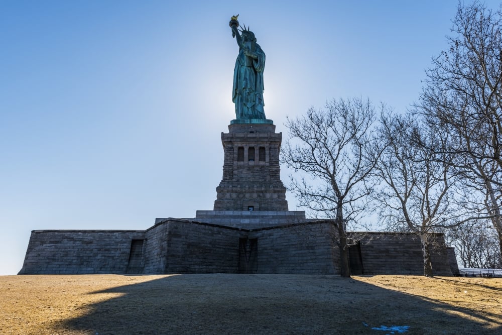 Sun Setting Behind The Statue of Liberty Liberty Island - New York City United States of America Poster Print - 19 x 12 in.