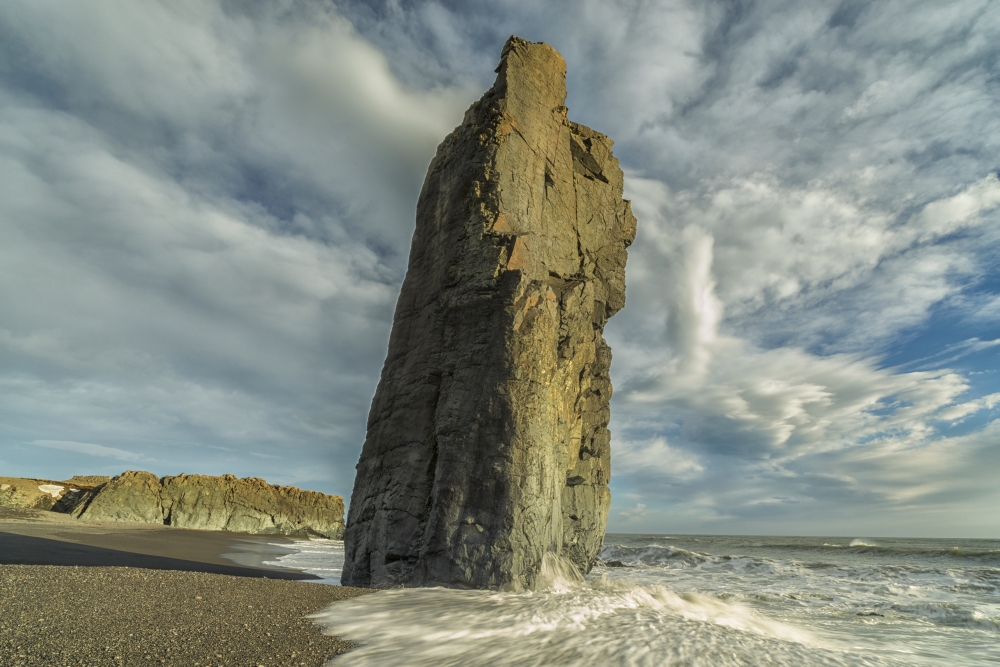 A Sea Stack Rises Out of The Bedrock While Waves Crash Against It Along The Beaches of The East Fjords - Iceland Poster Print - 19 x 12 in.