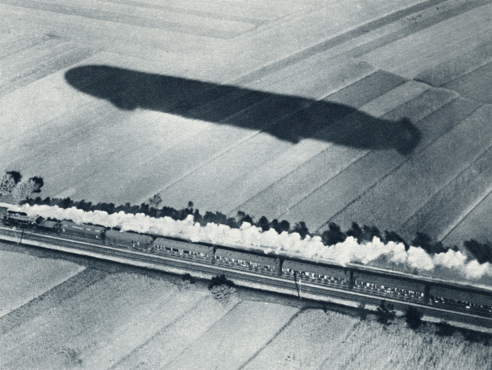 Shadow of The Fast Zeppelin Air Ship Schwaben Keeping Pace with An Express Train From The Illustrated War News - 1915 Poster Print - 16 x 12