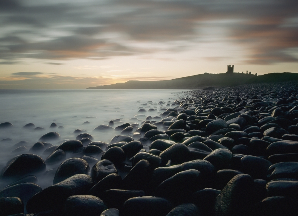 DPI1884786LARGE Looking Along Boulder Covered Beach Towards Dunstanburgh Castle At Dawn Poster Print, 36 x 26 - Large