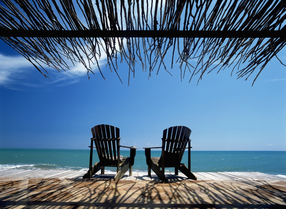 Two Chairs On Deck By Ocean Shaded By Grass Roof Poster Print