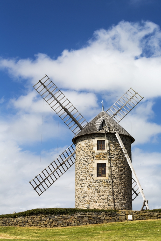 An Old Stone Windmill on A Hillside with Wooden Blades Surrounded Poster Print by A Stone Fence with Blue Sky & Clouds - Brehec 1 - 12 x 19 in.