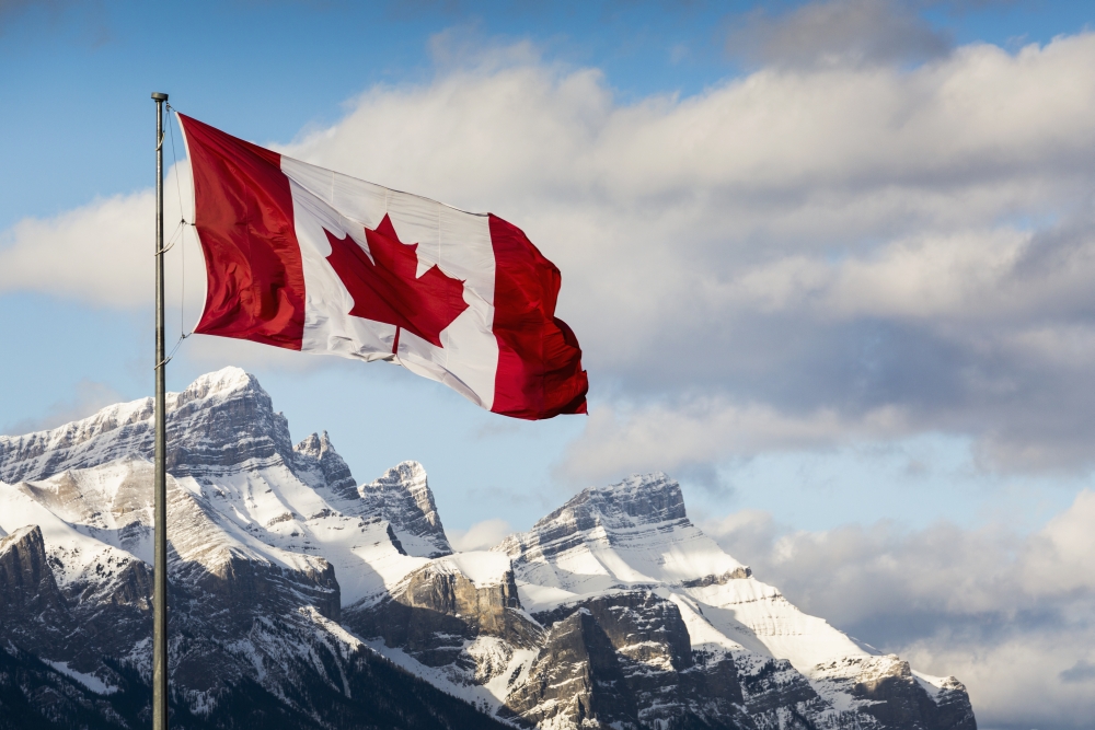 Canadian Flag Blowing in The Wind on A Flag Pole with Snow Covered Mountain Range in The Background with Blue Sky & Clouds Poster Print - 19 x 12 in.